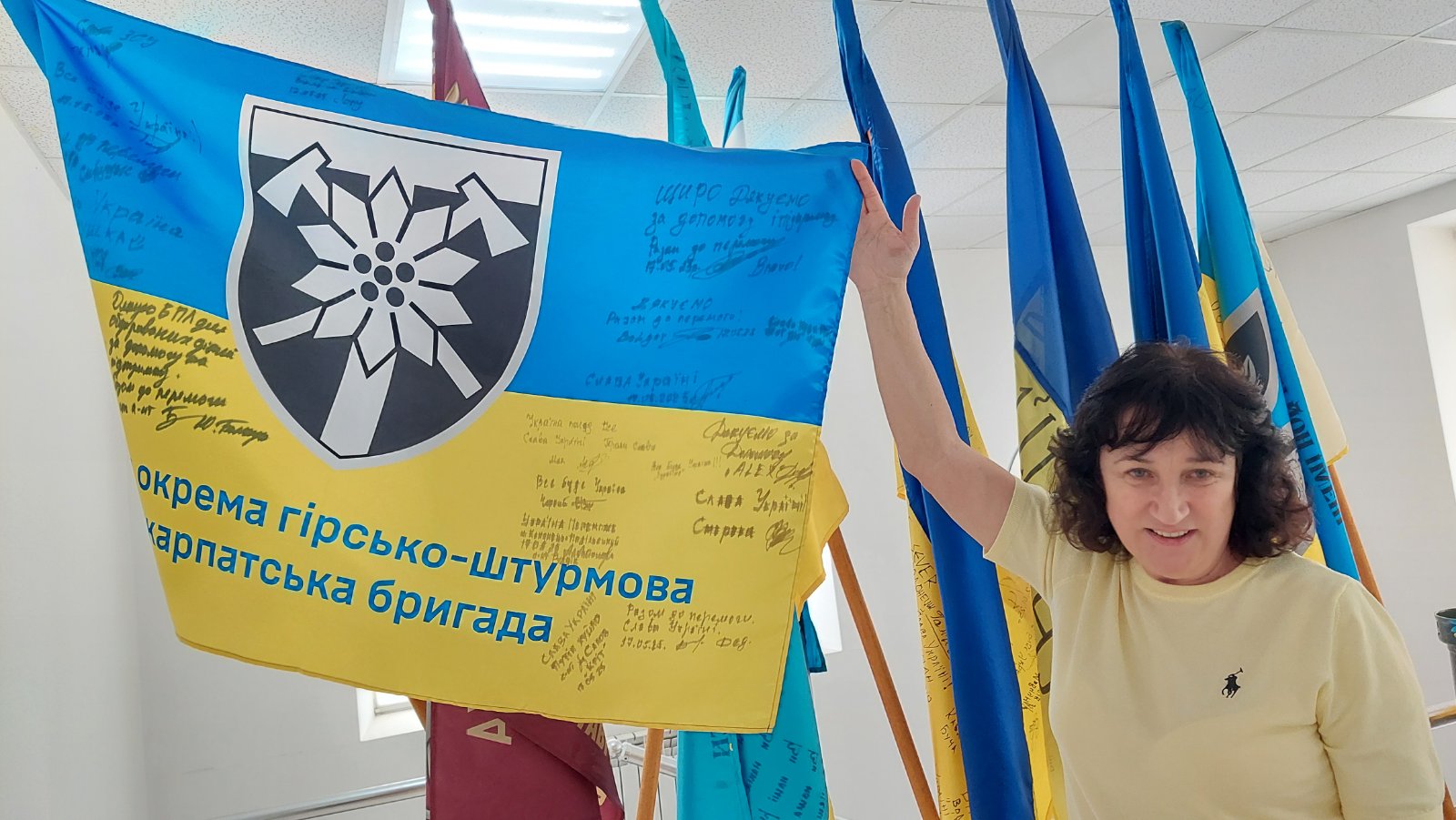 Заслужена вчителька України Ольга Осовська показує прапори військових бригад