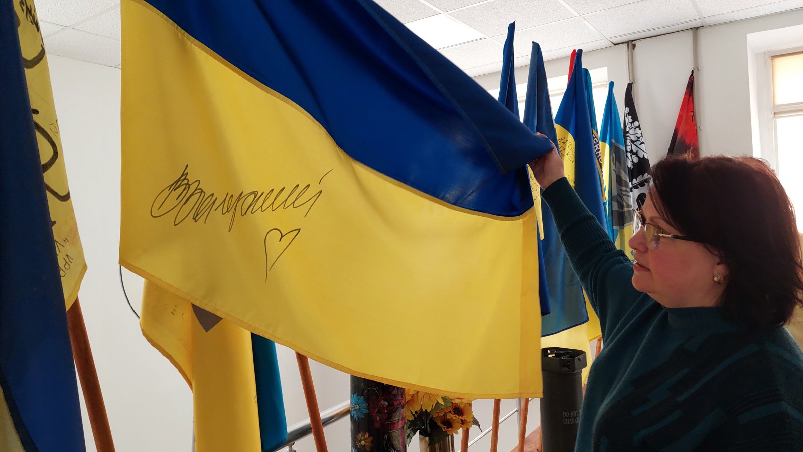 Заступниця директорки ліцею Ірина Тарангул пишаються прапором з автографом Генерала Залужного